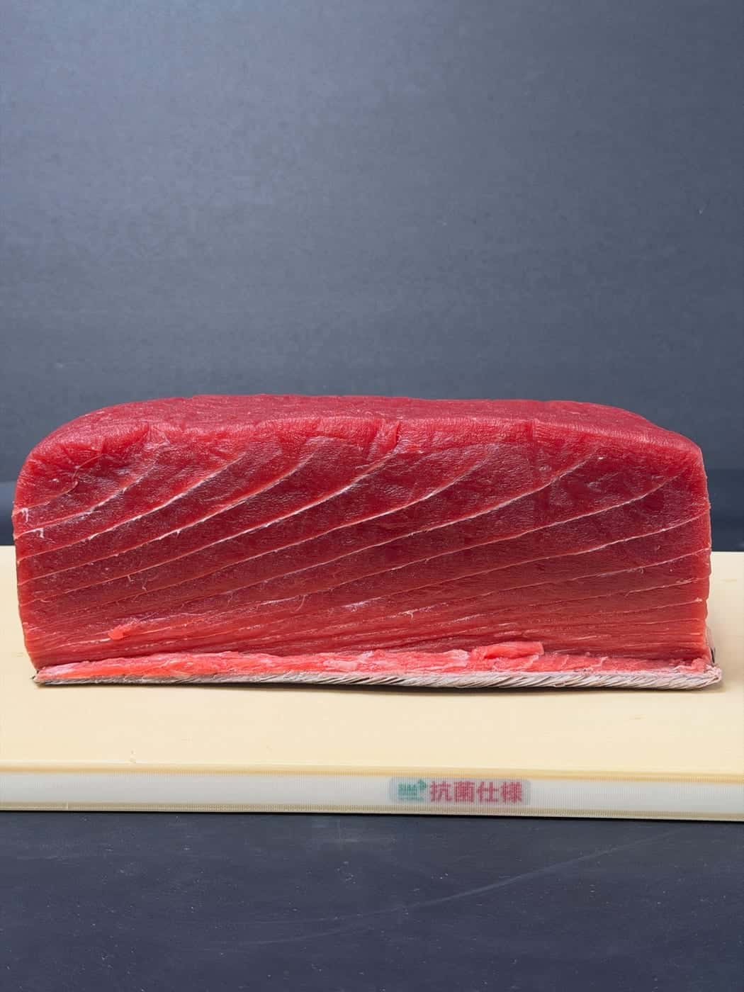 A fresh Atlantic bluefin tuna loin on a cutting board, the grain running in long curves