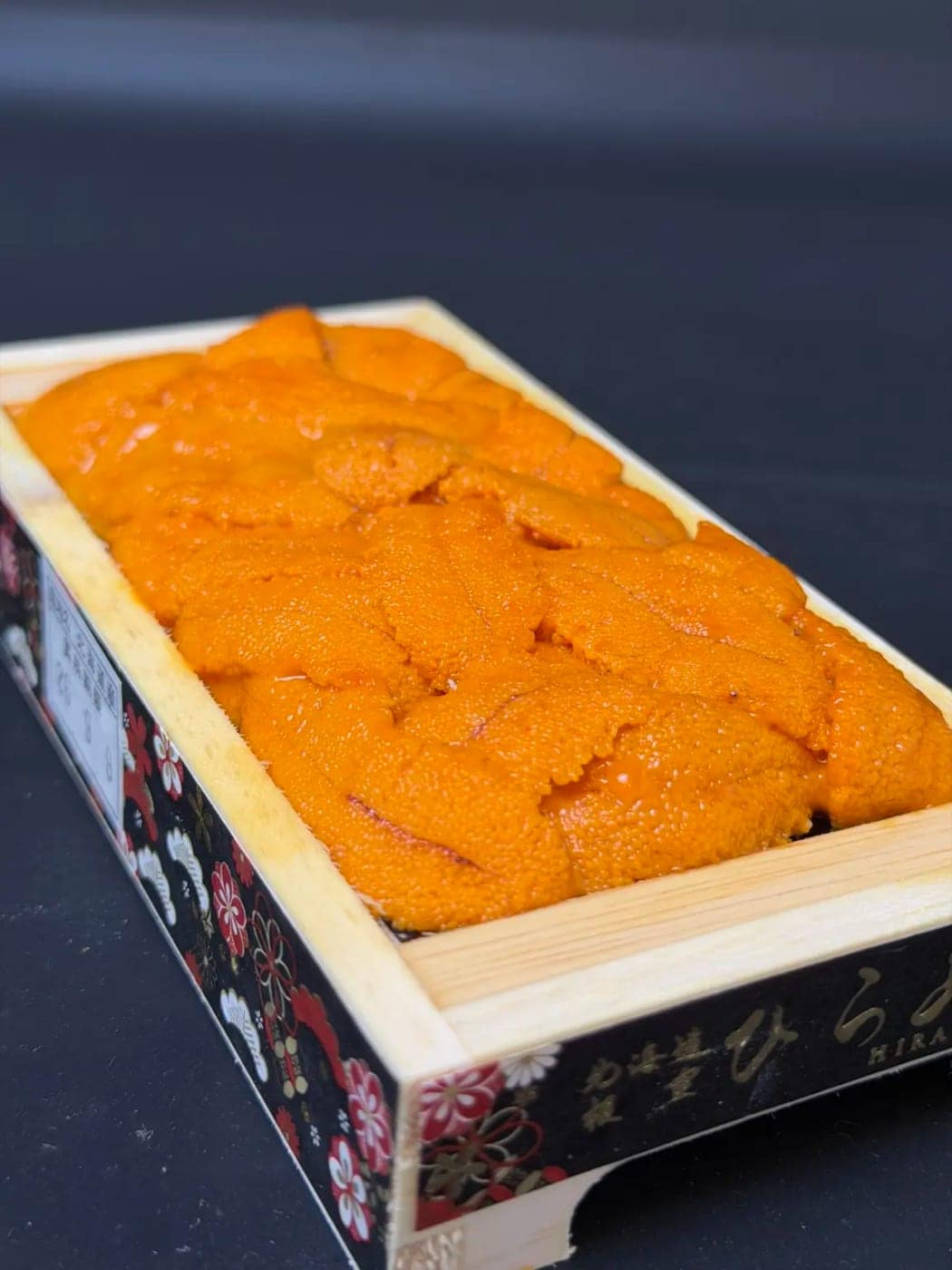 A wooden tray of Hokkaido uni, bright orange lobes side by side