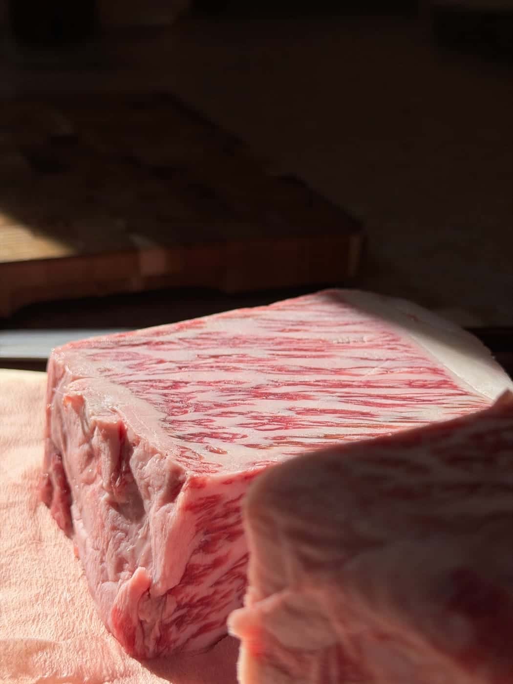 A cut block of Japanese A5 Wagyu in low afternoon light, the marbling catching the sun