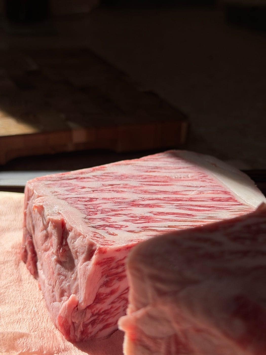 A cut block of A5 Wagyu in low sun, the marbling lit from the side