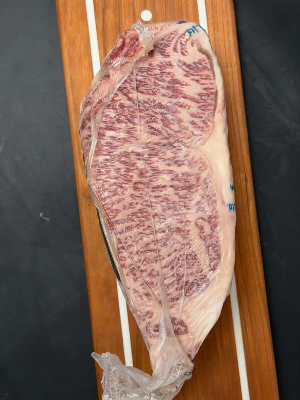 A whole Japanese A5 Wagyu strip loin, vacuum sealed, on a cherry board